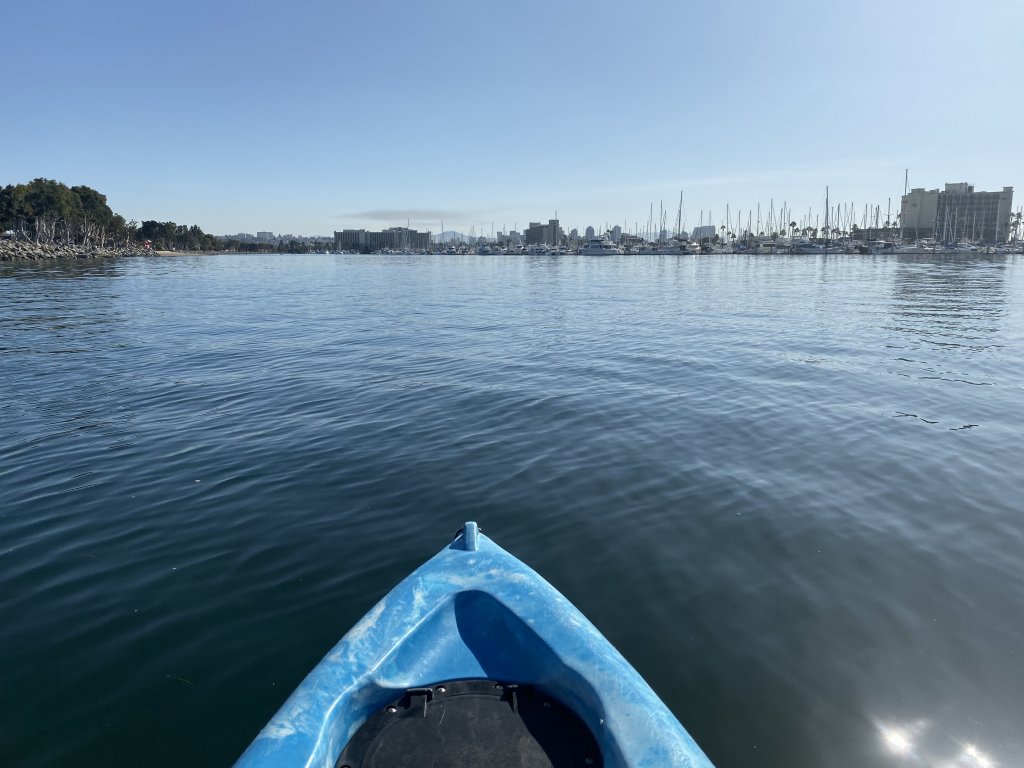 Looking out from a blue kayak at San Diego's boats and skyline