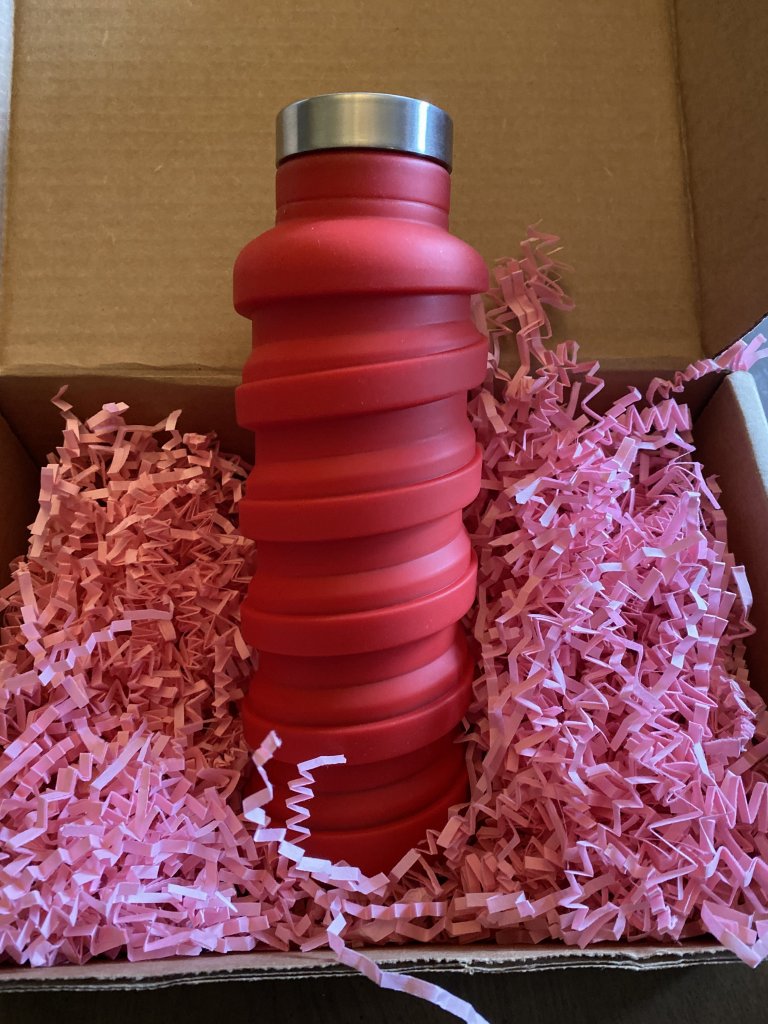 Red que Bottle extended to full length, in box full of pink raffia