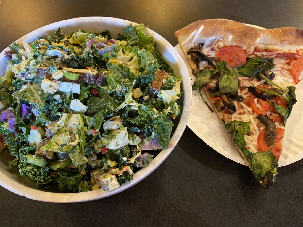 A giant kale salad and a slice of pizza