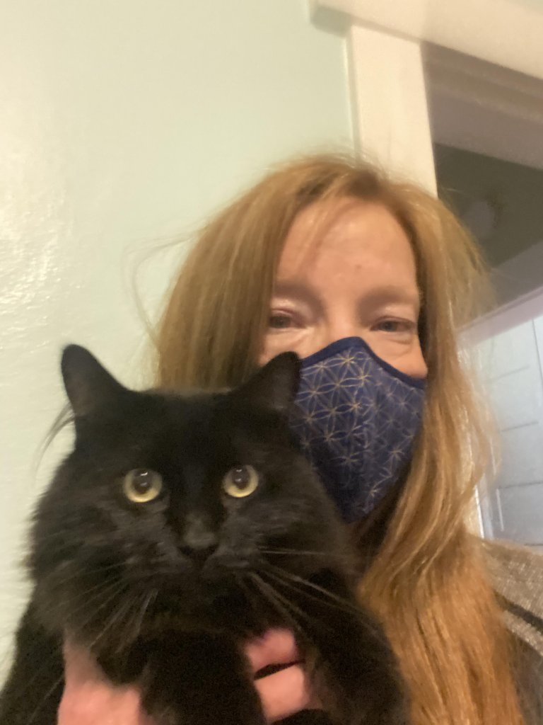 A woman wearing the Halo mask and holding a black cat