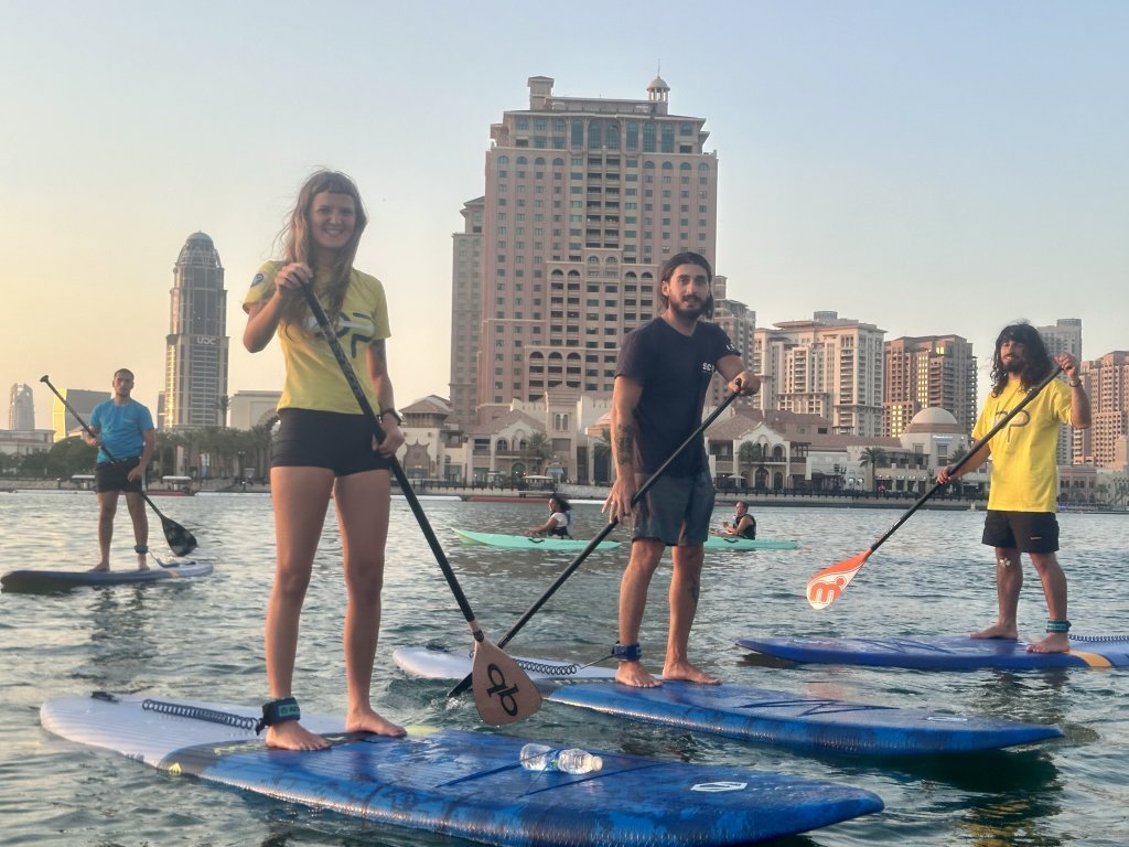 People on paddleboards in front of tall buildings.